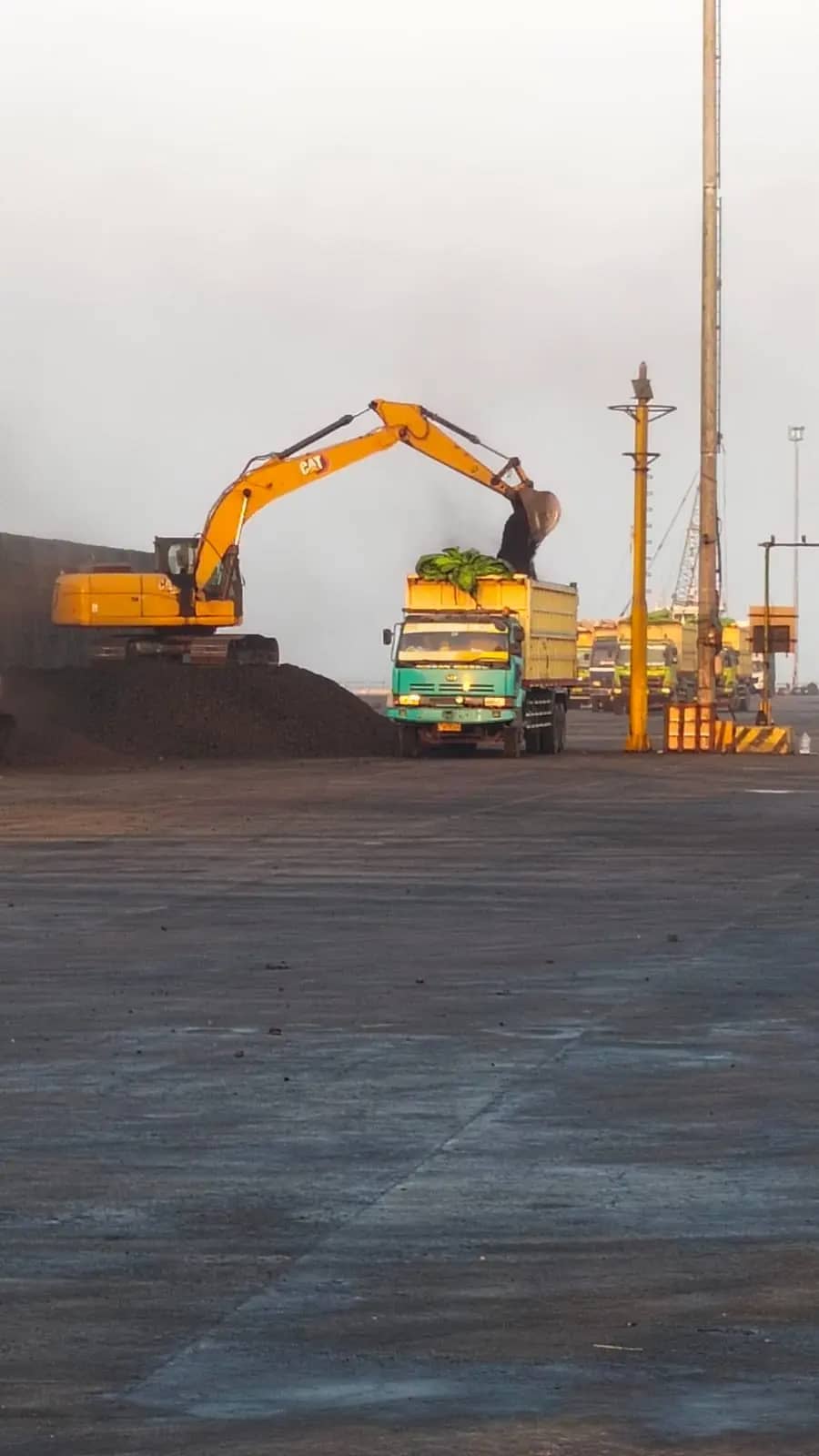 Excavator memuat material curah ke truk